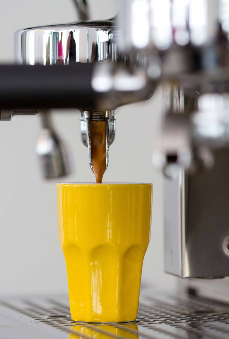 Espresso läuft in gelbe Tasse